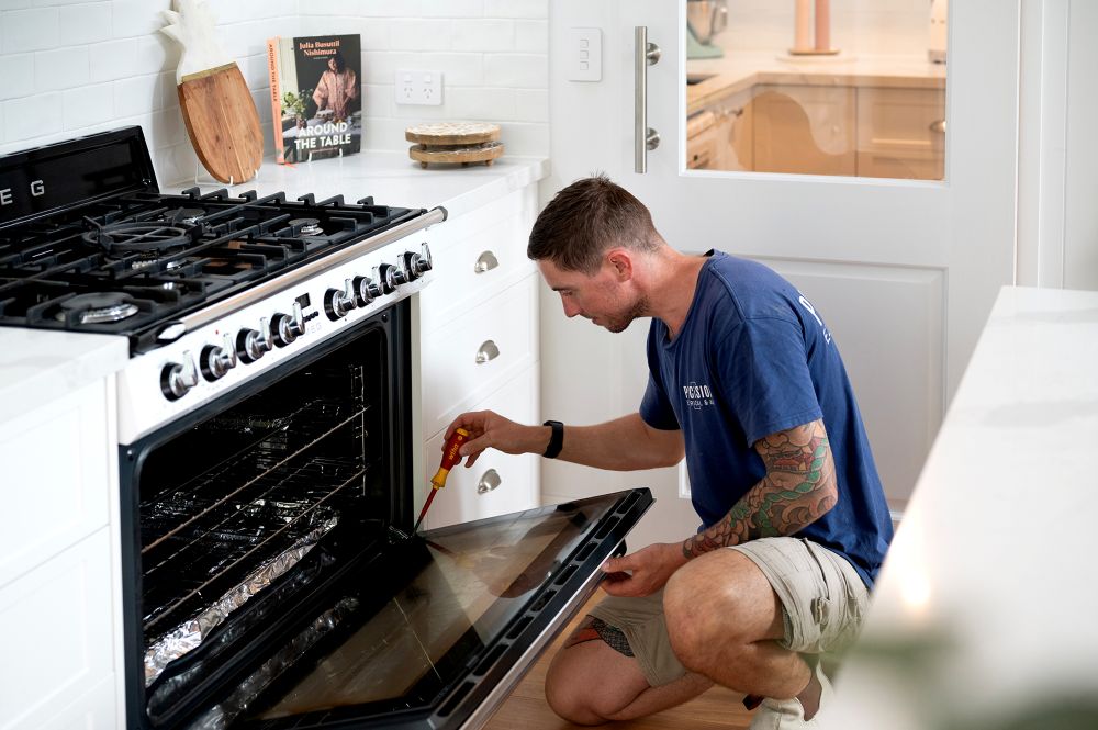 Licensed Precision electrician repairing an oven in a Brisbane kitchen