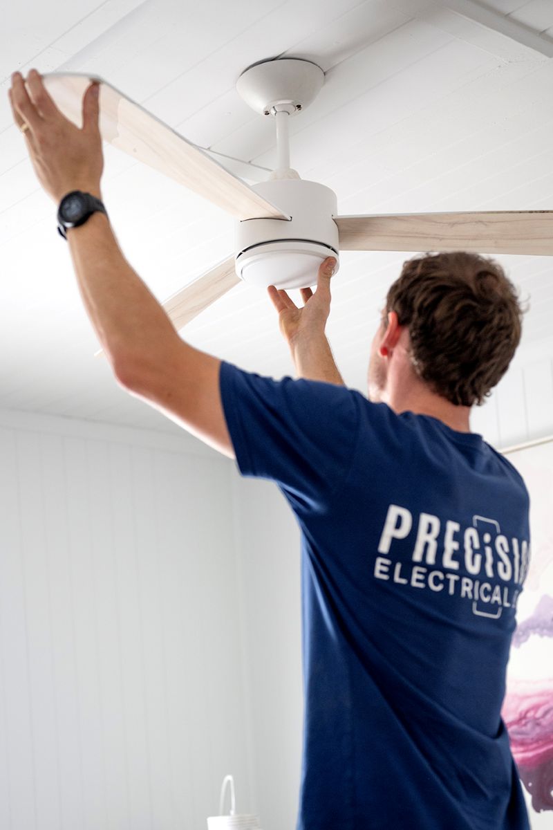 Electrician installing a ceiling fan in a Brisbane home